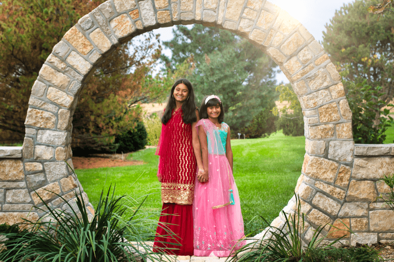 Sisters holding hands in the middle of a stone arch