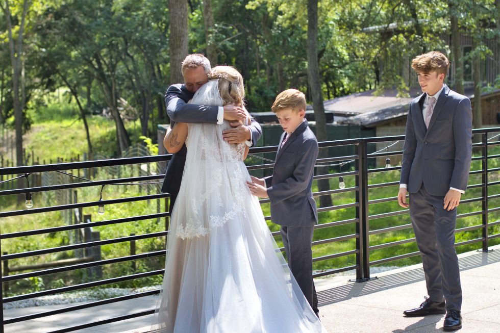 Bride hugging her dad while two younger boys watch